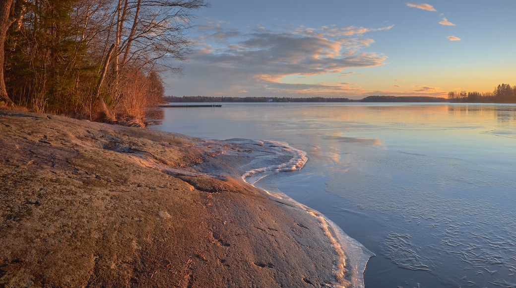 Panorama of the shores of Tuusula lake on a sunny winter day in Jarvenpaa: thin ice stone, sunbeams and bright sky.