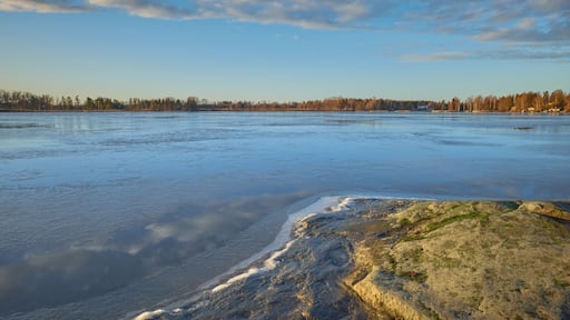 Panorama of the shores of Tuusula lake on a sunny winter day in Järvenpää: thin ice stone, sunbeams and bright sky.
