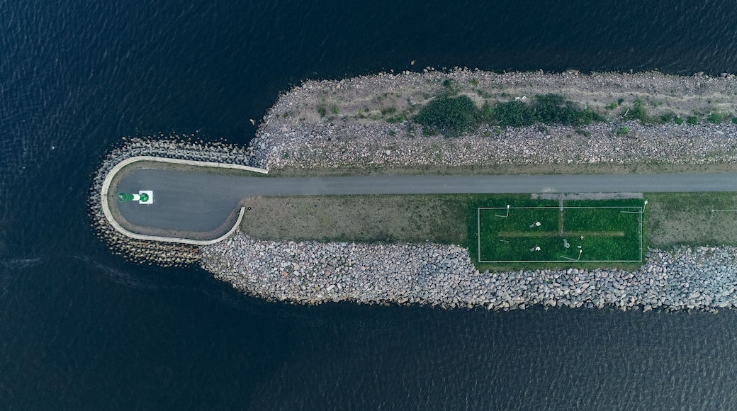 Aerial view of the Lighthouse on the fairway in the Gulf of Finland, navigation is open, summer time. Concrete slabs on the coastline. Breakwaters at the entrance to the port.