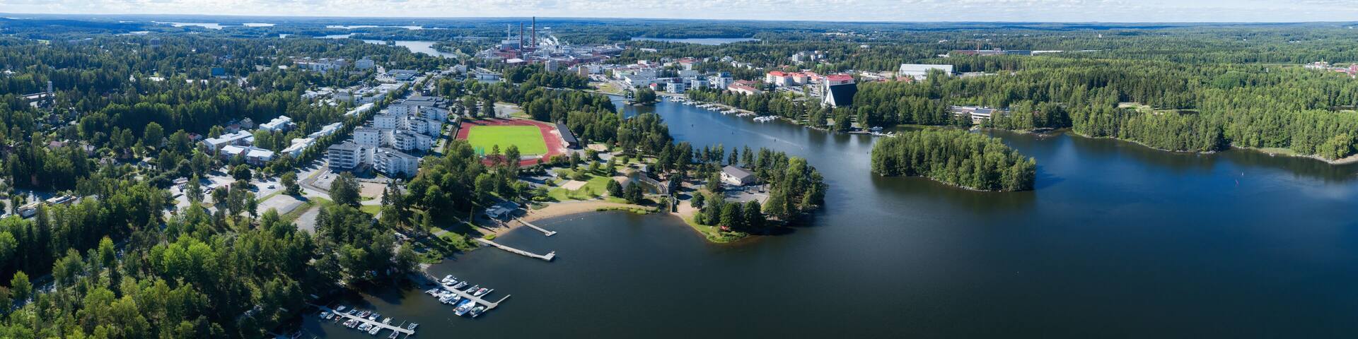 Beautiful view of Valkeakoski city at sunny summer day with blue sky and clouds. Aerial view of blue lake with bridge and green summer town in Finland.
