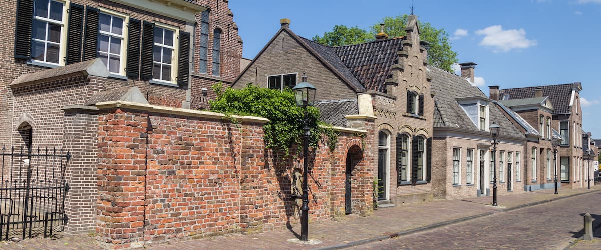 A historic street with brick buildings, a cobblestone road, and a clear blue sky.