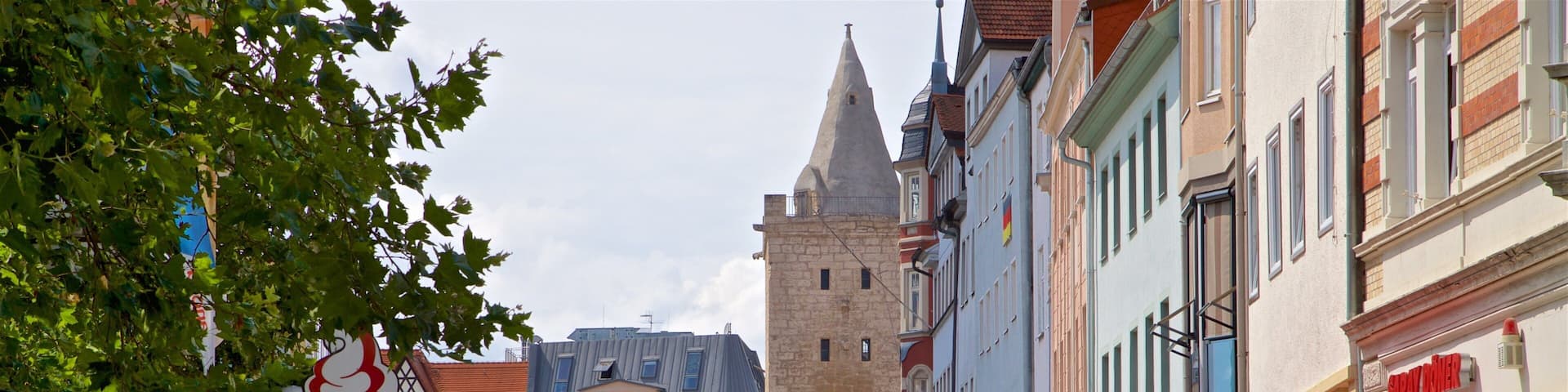 A bustling European street with historic buildings, outdoor cafes, and a prominent tower.