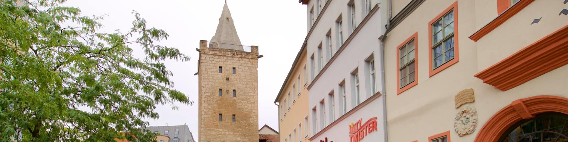 A cobblestone square with outdoor seating, a historic tower, and a restaurant named "König".