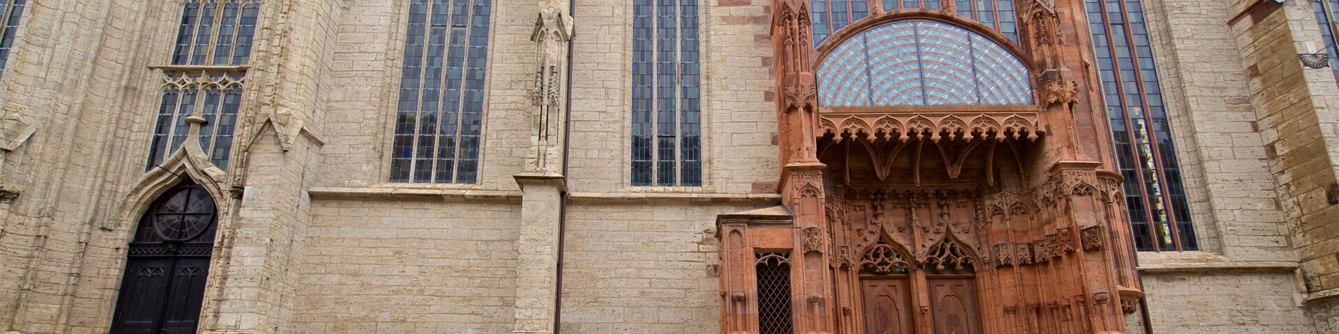 Un edificio histórico con amplias ventanas de arco y elaborados adornos de piedra.