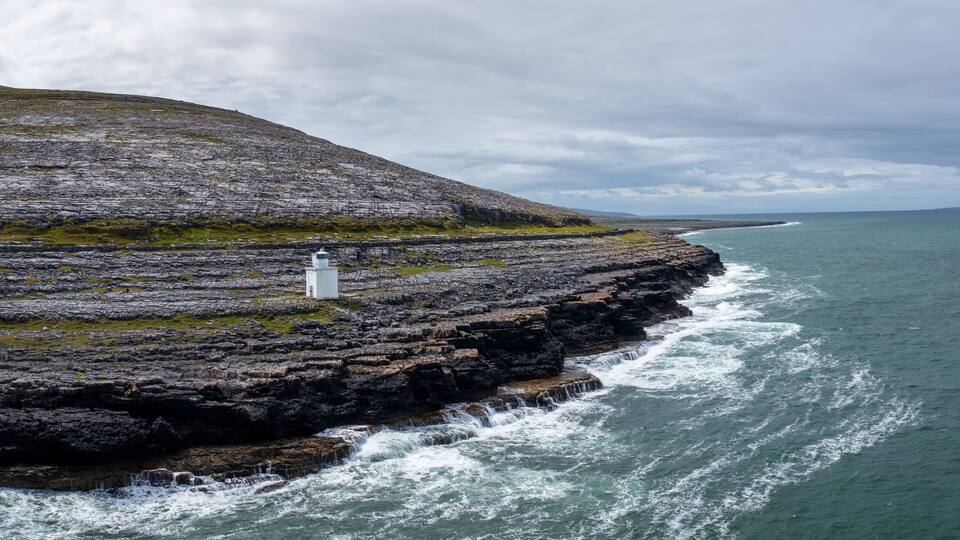 A rocky coastline with a lighthouse on a cliff.