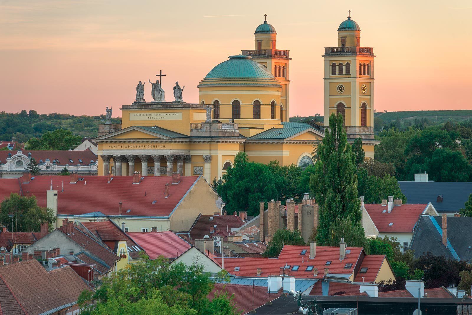 A historic church with a prominent dome and twin bell towers, surrounded by residential buildings and greenery.