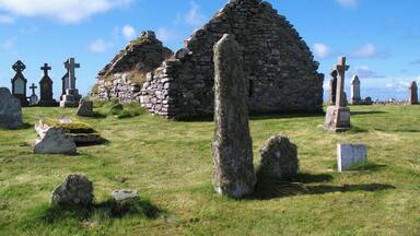 A stone structure with crosses and tombstones in a grassy field.
