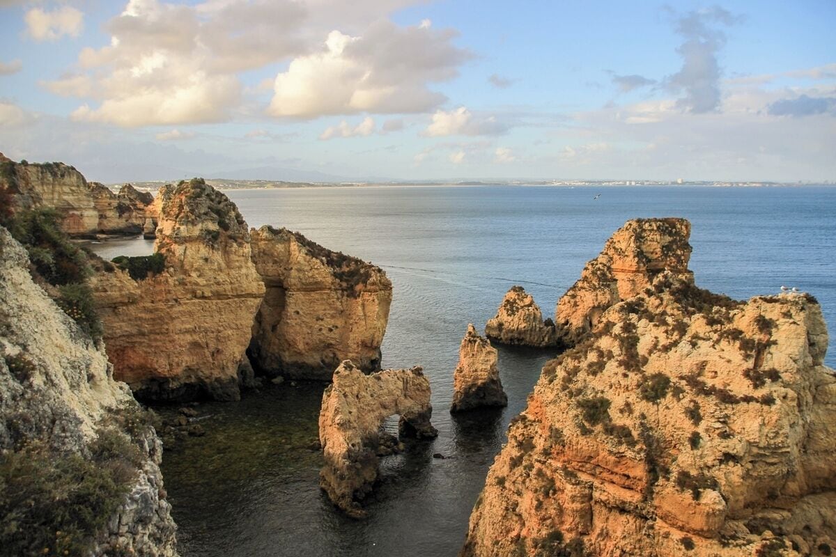 Un paisaje costero con formaciones rocosas destacadas y un mar tranquilo.