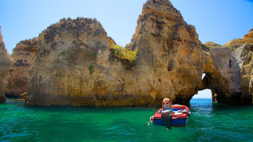 A rocky coastal landscape with a boat near a natural arch formation.