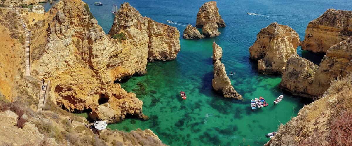 A coastal landscape with rocky cliffs, clear turquoise waters, and a narrow sea passage.