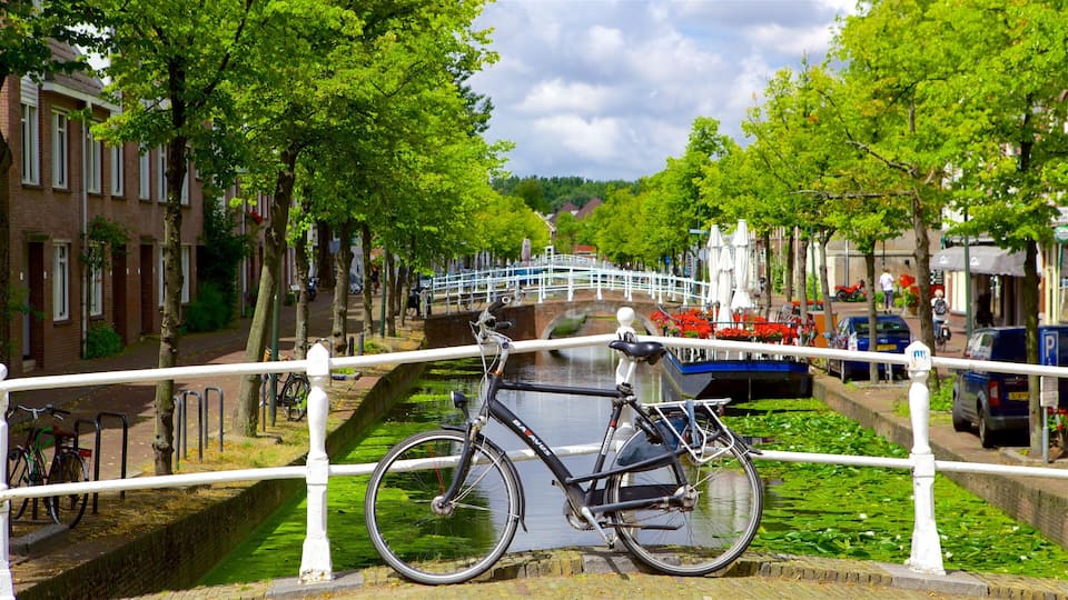 A canal with a bicycle parked by the railing, a bridge in the background, and buildings along the canal.