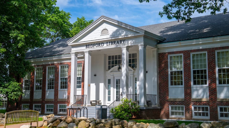 A brick building with a white facade and the Bedford Library sign.
