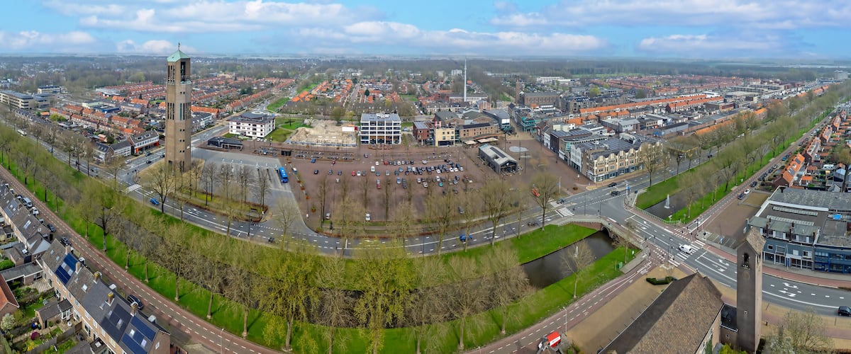 A panoramic view of a city with a prominent tower, a river, and a mix of residential and commercial buildings.