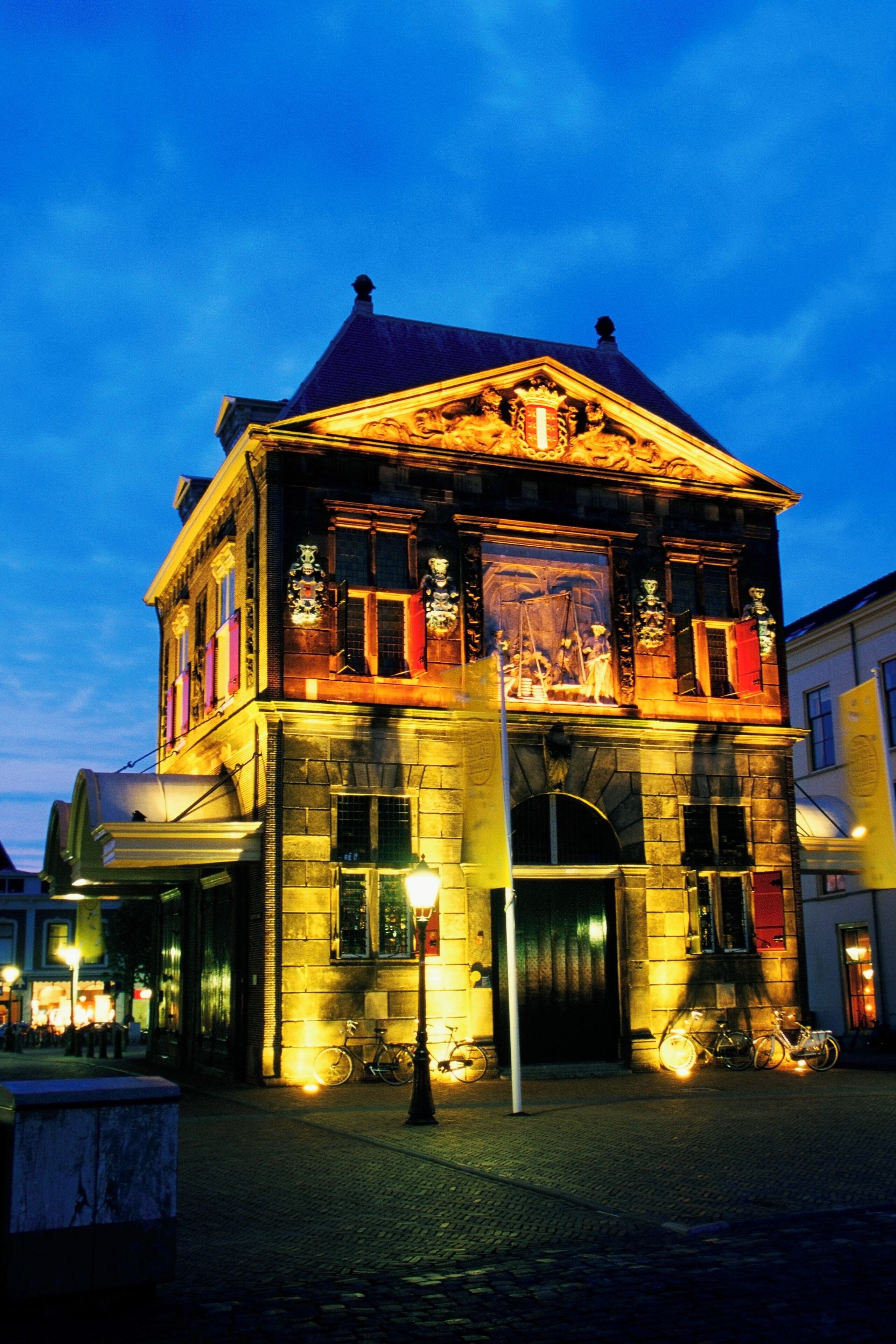 A historic building with ornate architecture and a clock tower, illuminated at dusk.