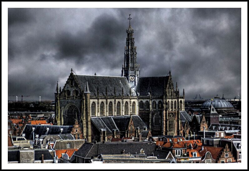 Une cathédrale gothique, dotée d’une haute flèche et d’une tour horloge, entourée de bâtiments historiques.