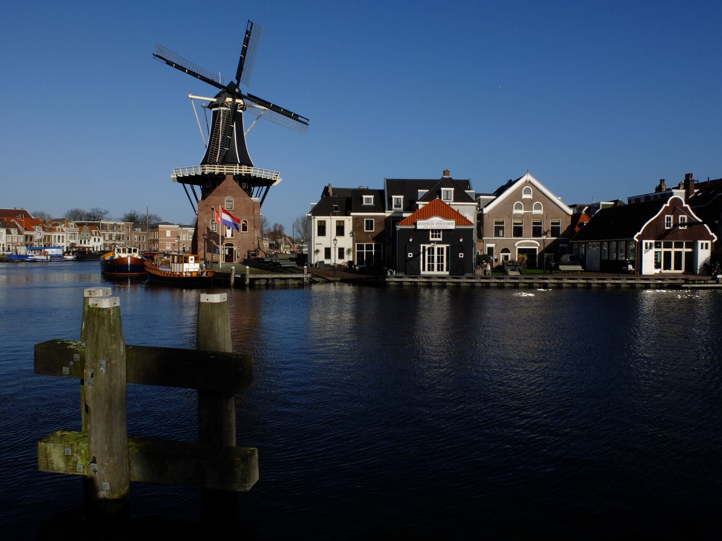 A traditional Dutch windmill, a canal, and historic buildings along the water's edge.