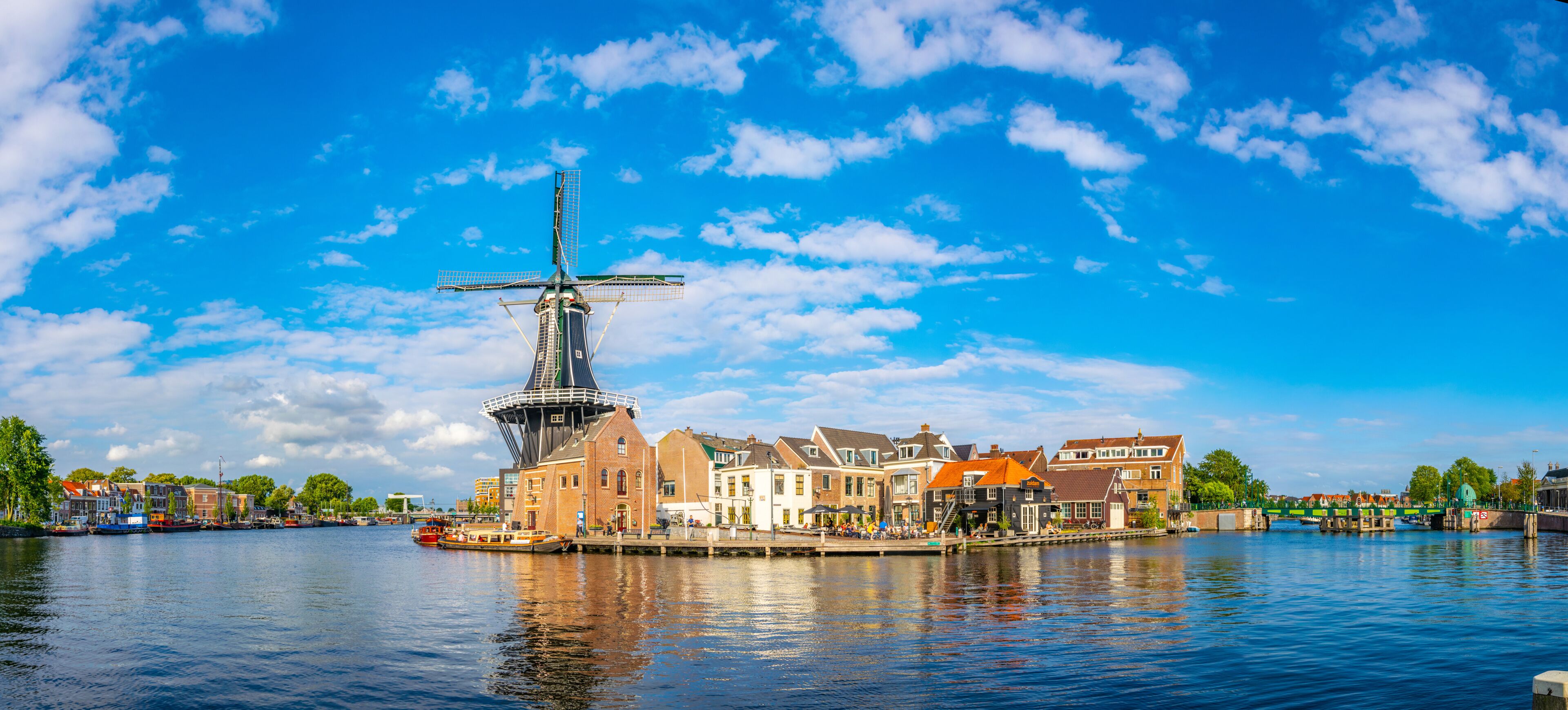 A canal with a windmill, traditional buildings, and a bridge.