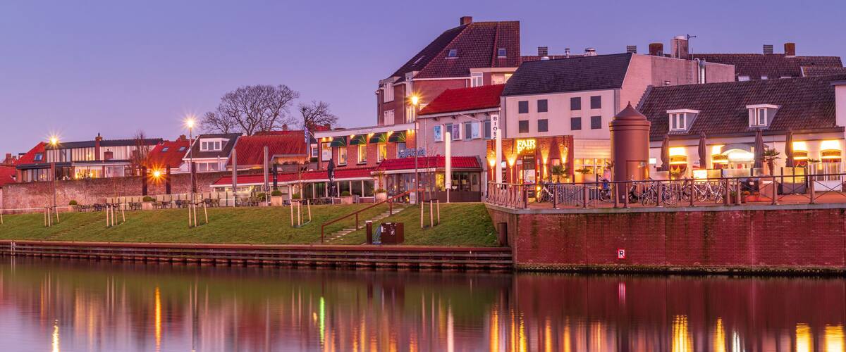 A riverside town with historic buildings, a bridge, and a canal.