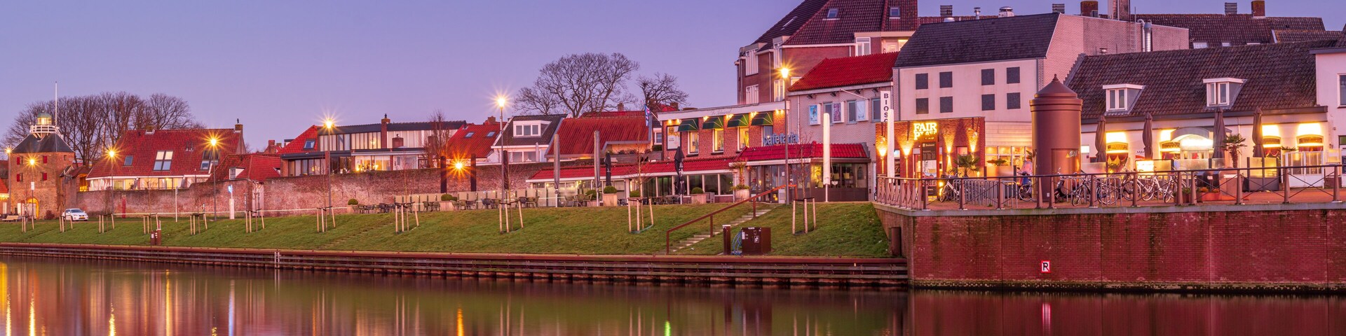 A riverside town with historic buildings, a bridge, and a canal.