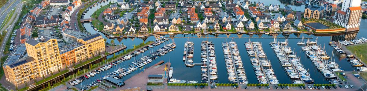 A riverside town with a marina, historic buildings, and a modern bridge.