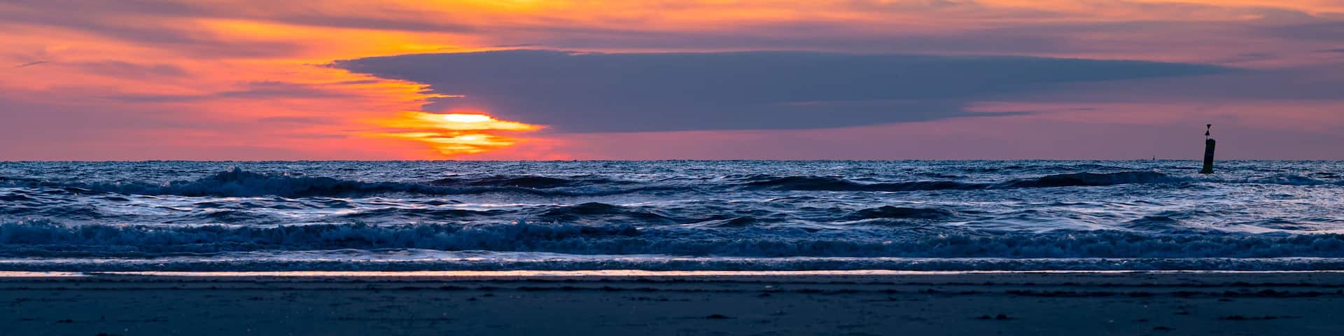 Panoramic view of a colorful sunset above the surf of the sea