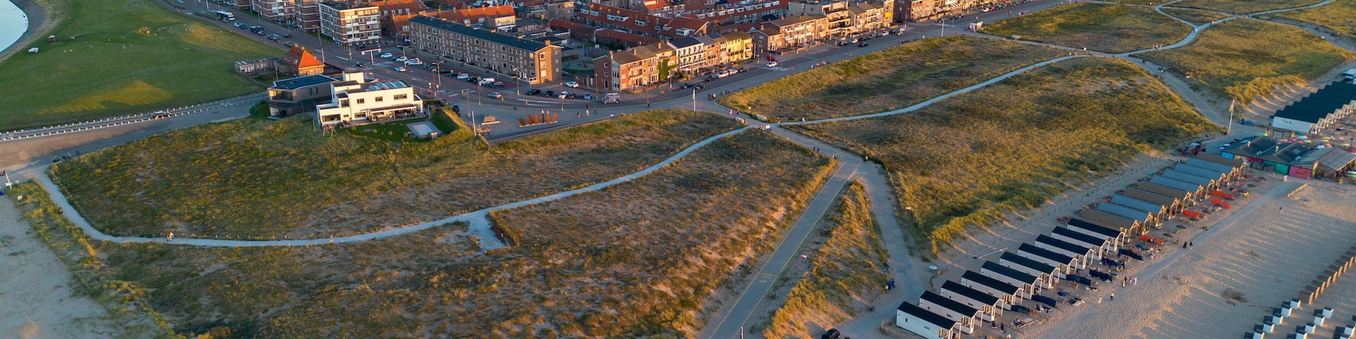 An aerial view of a coastal town with a dense urban area, a sandy beach, and a marina.