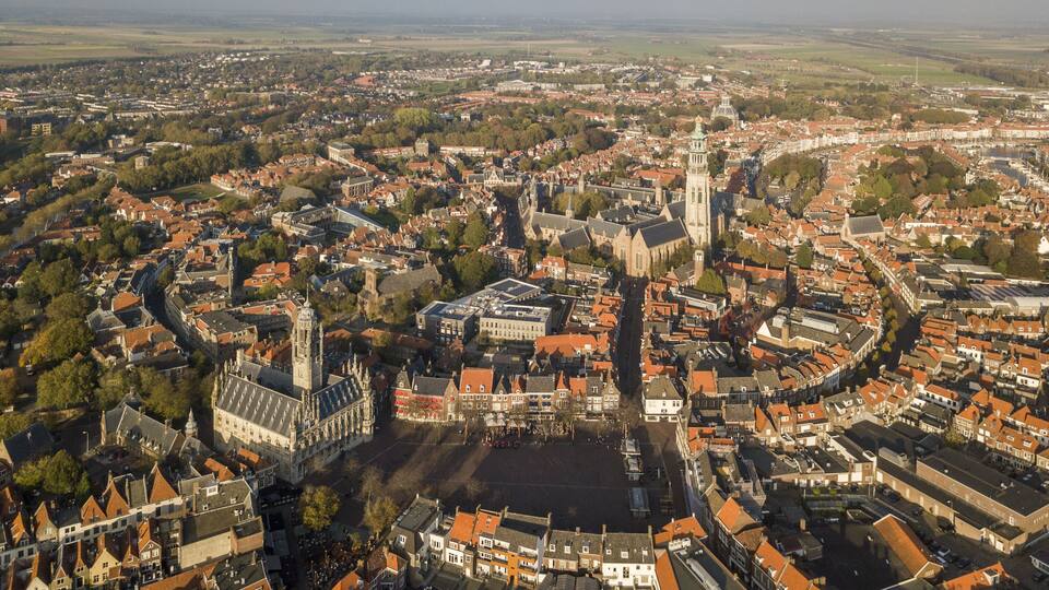 An aerial view of a historic town with a prominent church, a large square, and surrounding residential buildings.