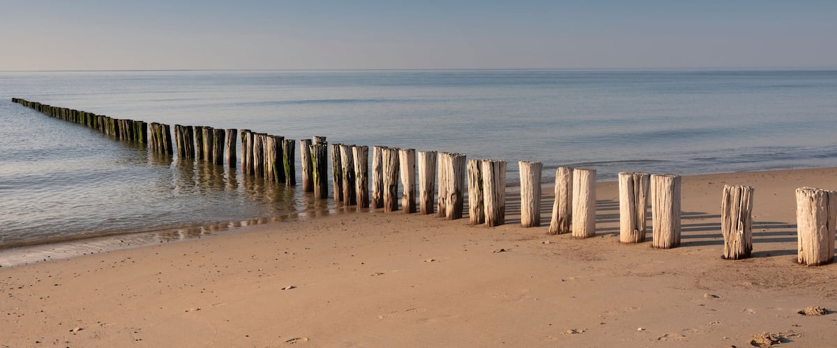 A sandy beach with a wooden groyne extending into the water.