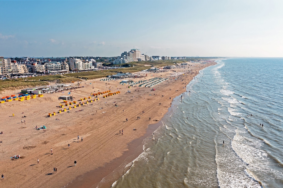 Een kuststrand met mensen, gebouwen en een heldere lucht.