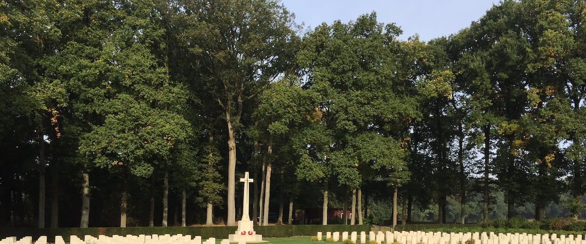 A cemetery with numerous headstones and a central cross monument.