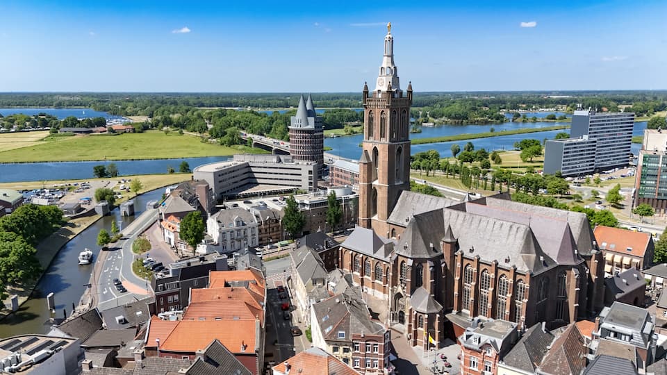 A historic cityscape with a prominent church tower, a modern building, and a river.