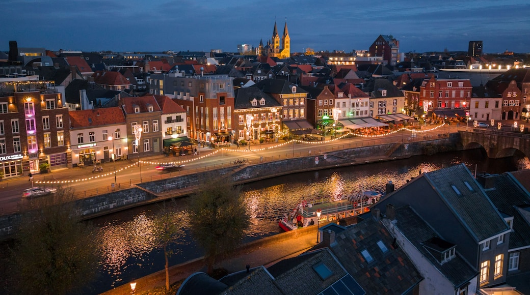 Aerial view of a canal reflecting the warm glow of evening lights along buildings and the Sint Christoffelkathedraal, Roermond, Limburg, Netherlands.