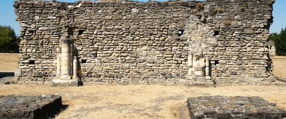 An ancient stone structure with columns and a dry, grassy field.