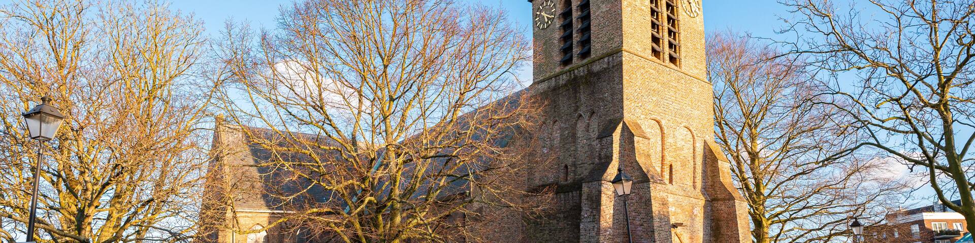 A historic church with a tall tower and a weather vane.