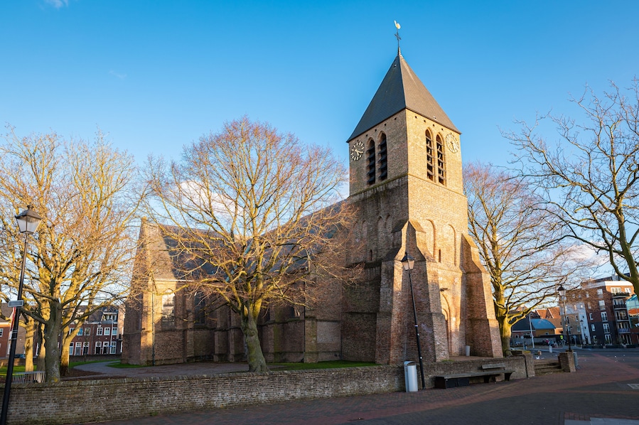 A historic church with a tall tower and a weather vane.