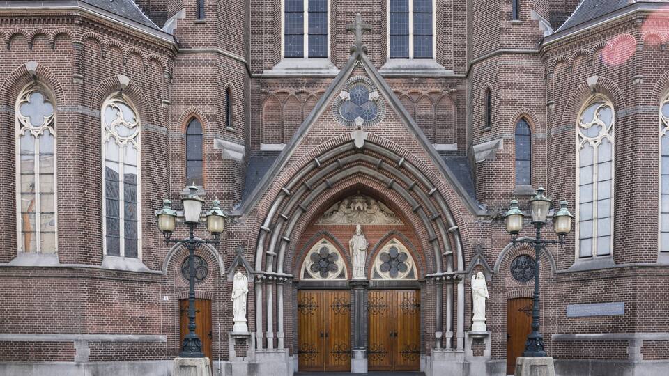 A historic church with a large wooden door, arched windows, and statues.