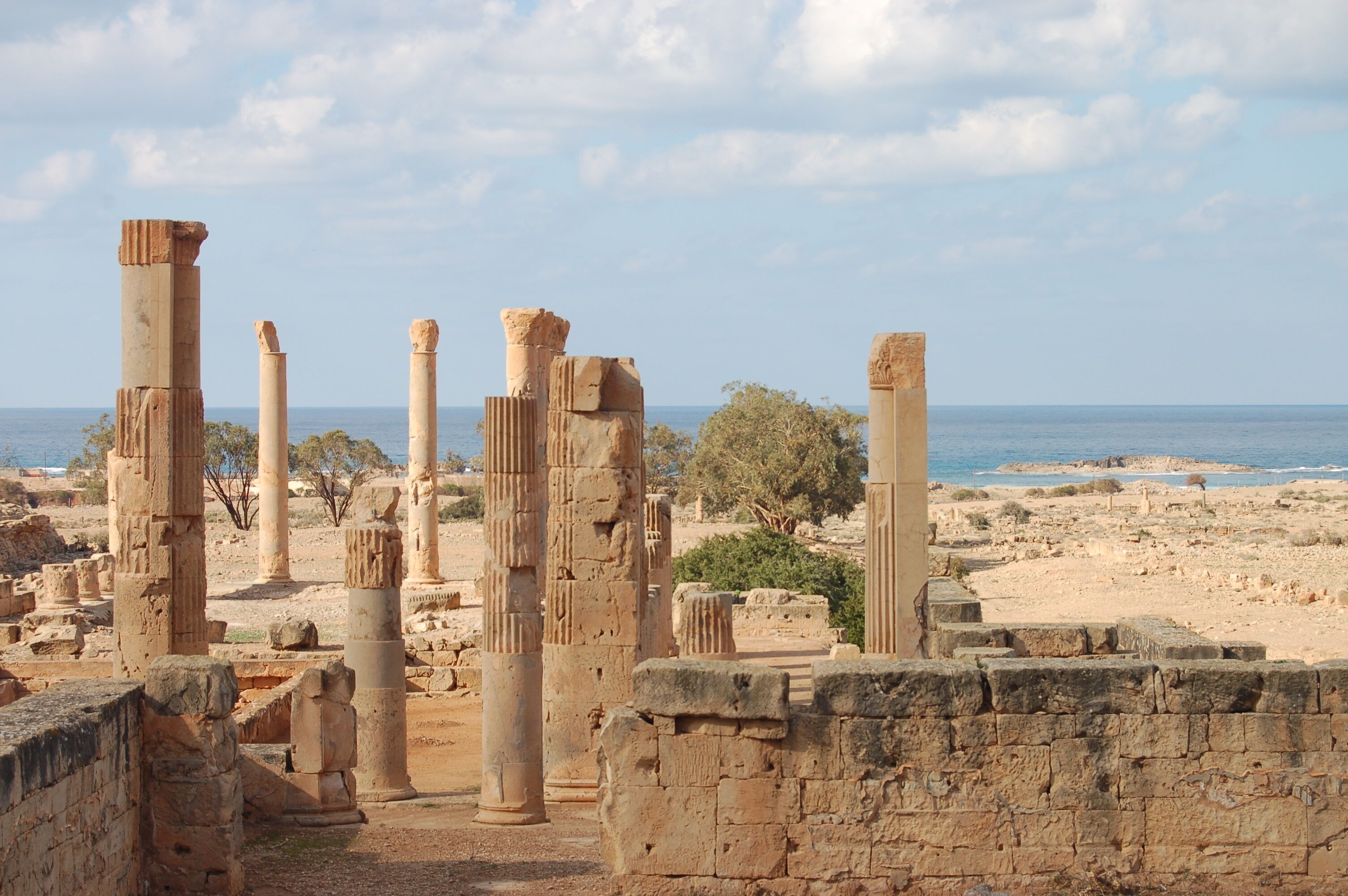 Ancient ruins with columns and a view of the sea.