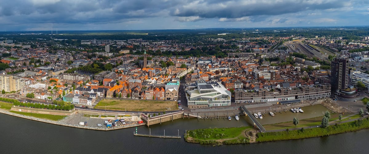 Bybillede med en flod, en bro og et stort stadion.