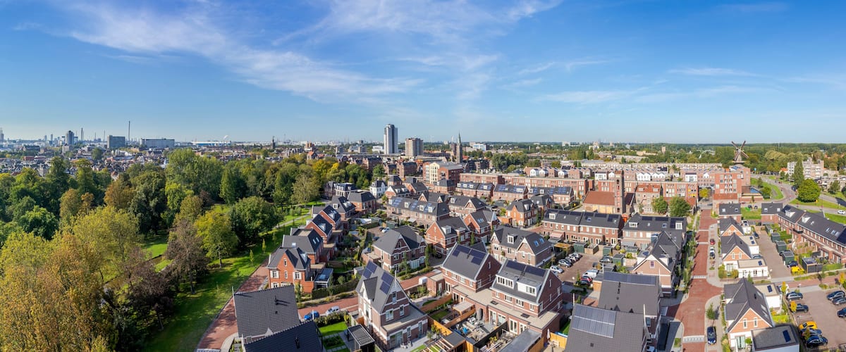 A cityscape with a mix of residential and industrial areas, a prominent windmill, and a clear blue sky.