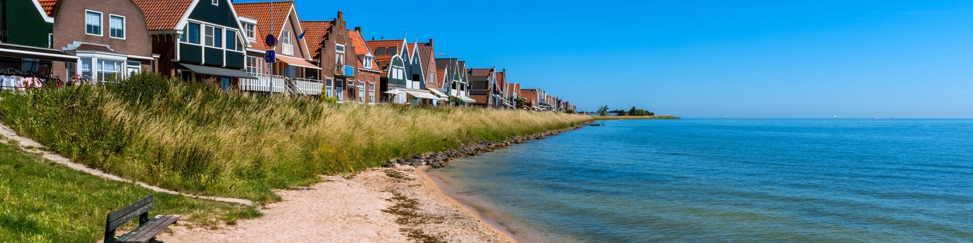 Un pueblo costero con casas tradicionales, una playa de arena y aguas tranquilas.
