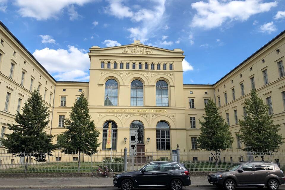 A classical building with arched windows and a statue in front.