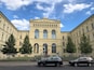 A classical building with arched windows and a statue in front.