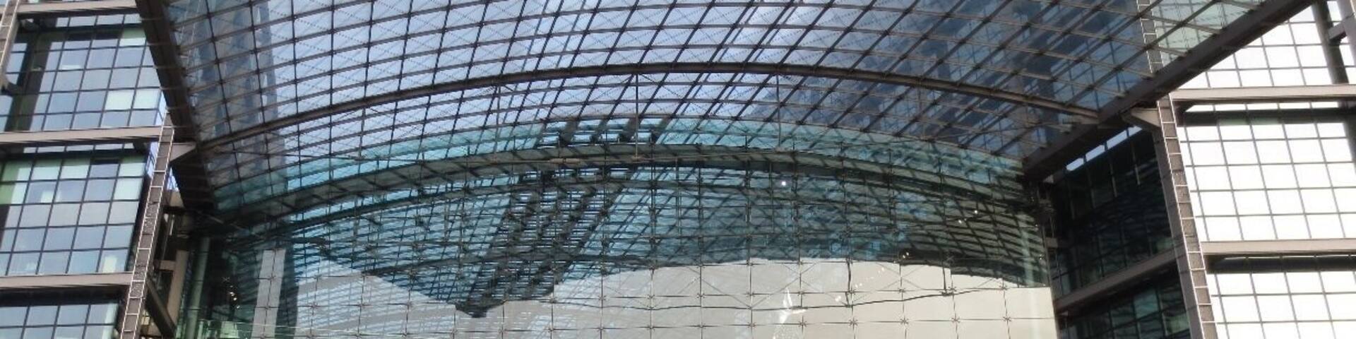 A modern glass building with the text "Berlin Hauptbahnhof" and a Christmas tree in front.