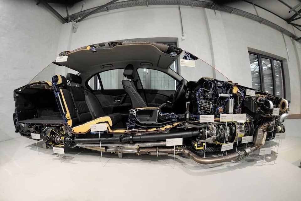 Un coche con el motor a la vista, varios componentes etiquetados y el capó entreabierto.