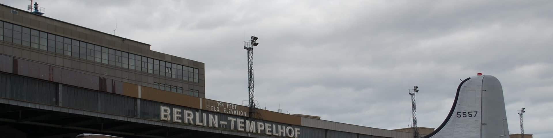 A vintage carrier airplane parked at an airport with a building labeled "BERLIN-TEMPELOHOF" in the background.