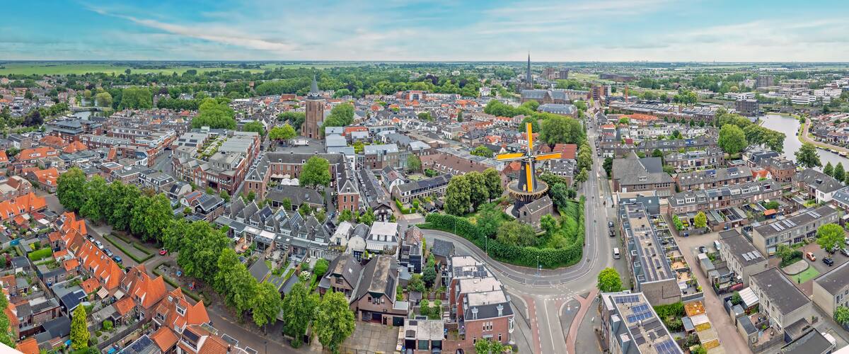 An aerial view of a city with a prominent church, a river, and surrounding residential areas.