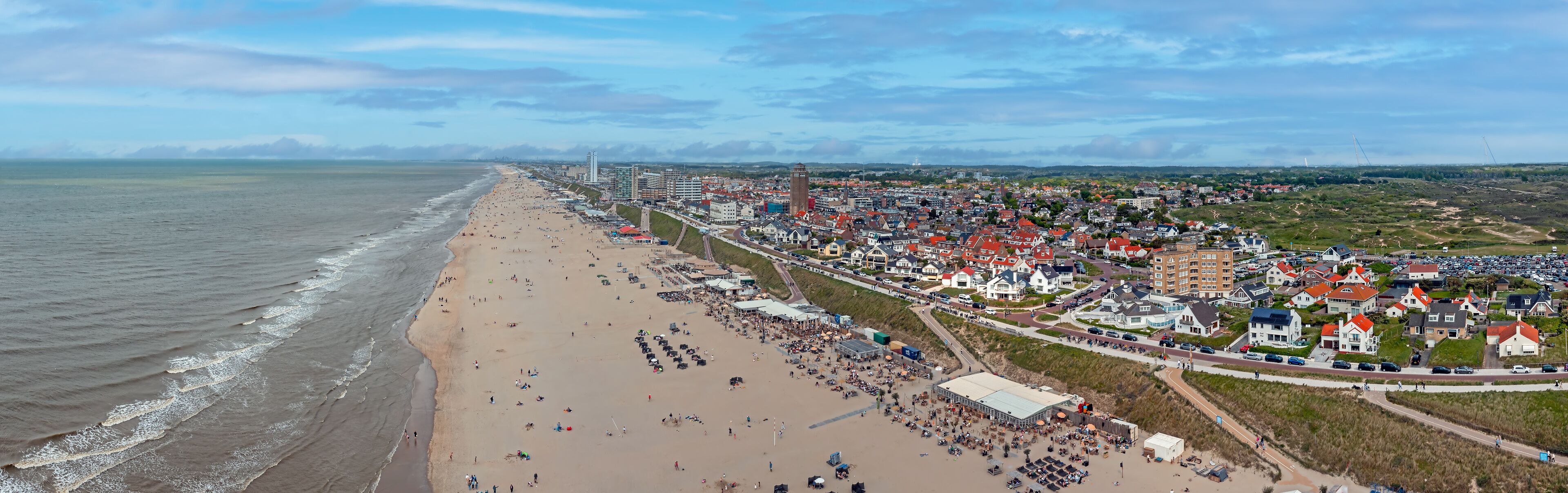 A coastal town with a sandy beach, a promenade, and residential buildings.