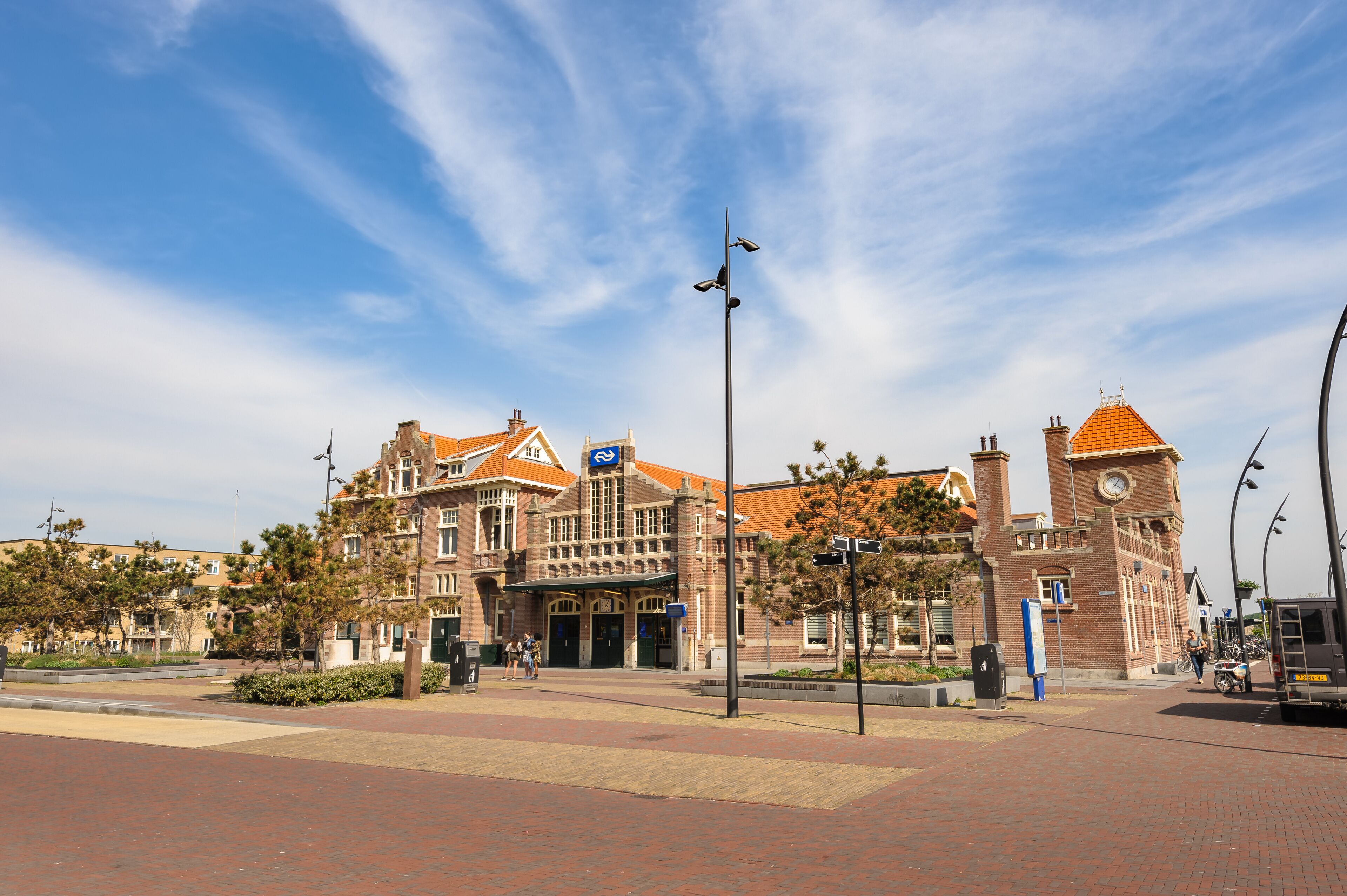 A historic building with a clock tower, a red-brick facade, and a blue sign.