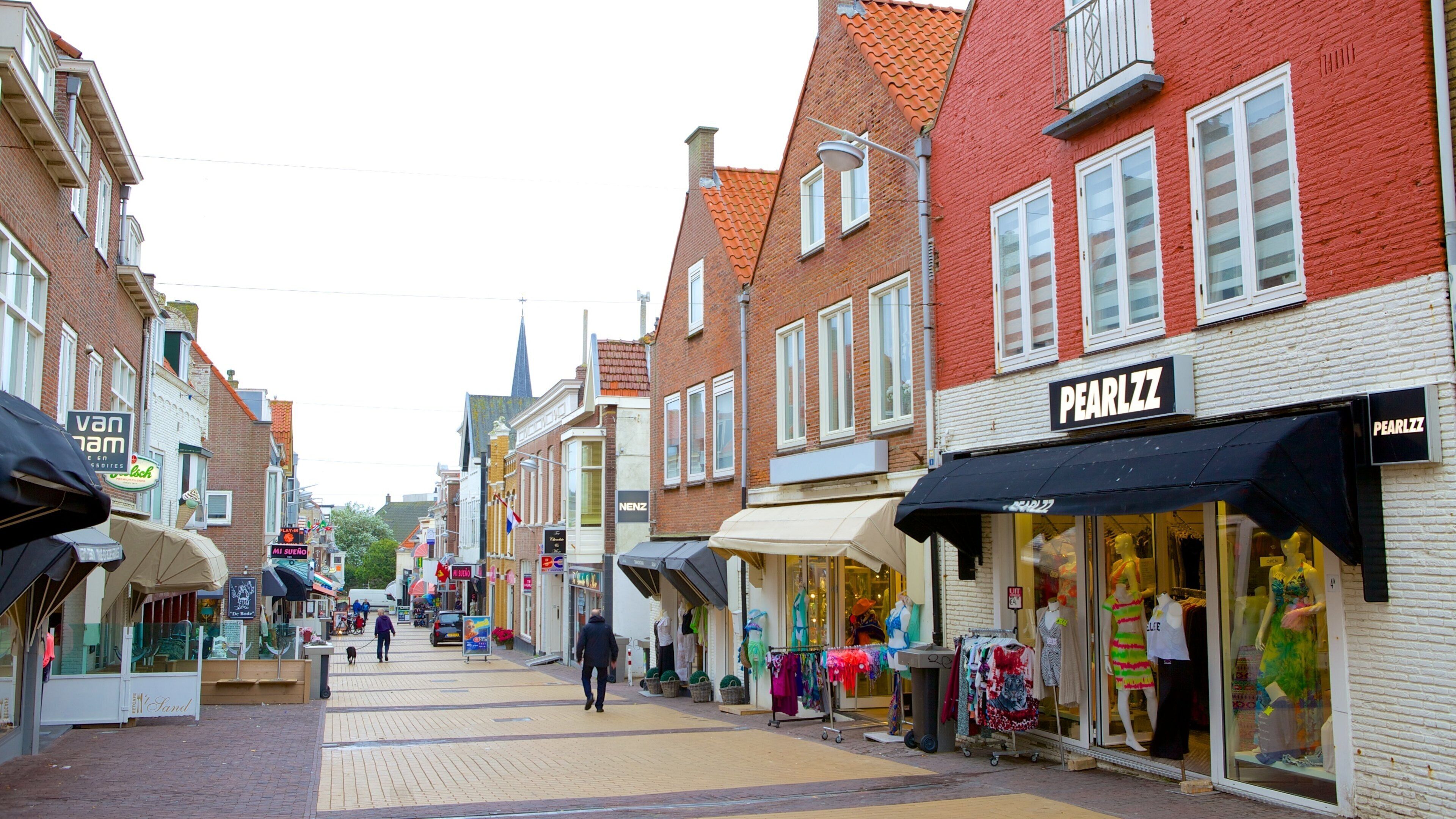 A street with shops, including a pharmacy and a clothing store.