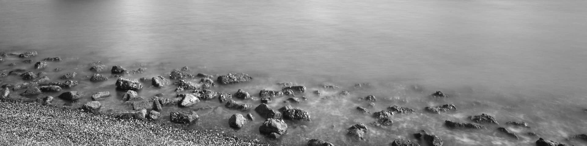 A bridge over calm water with a rocky shoreline.